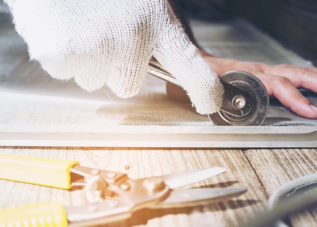 Warm and dark tone photo of a man is working with mosquito wire screen installation