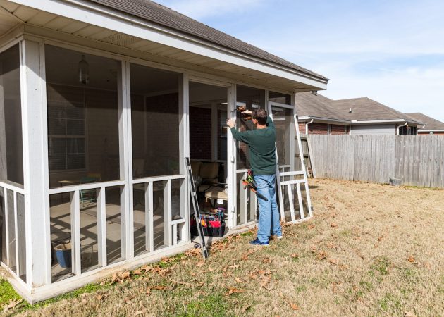 Repairman works on repairing door to screened in back porch